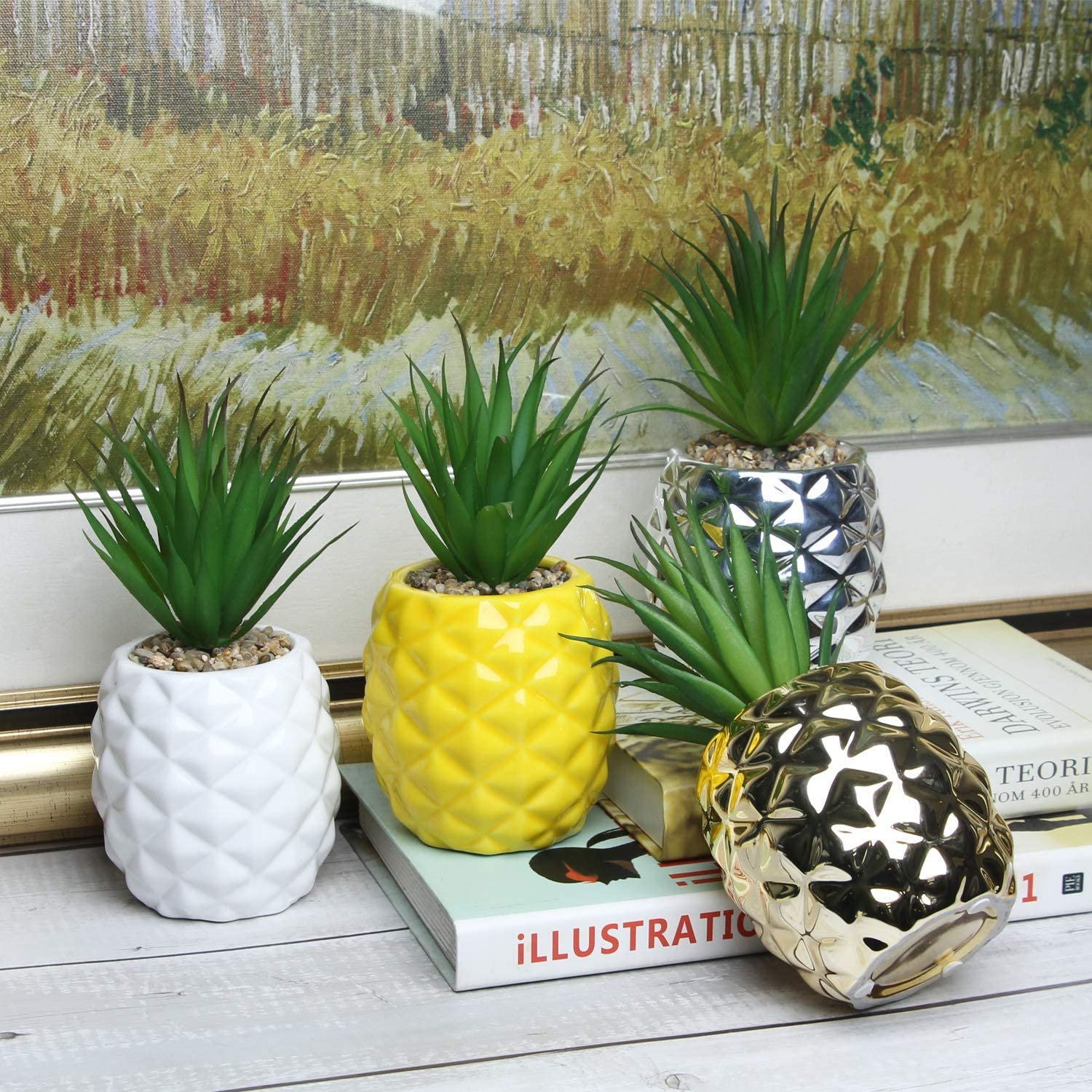 Four ceramic pineapple-shaped planters in white, silver, yellow, and gold, each containing a gorgeous fake plant, placed on books against a textured wall.