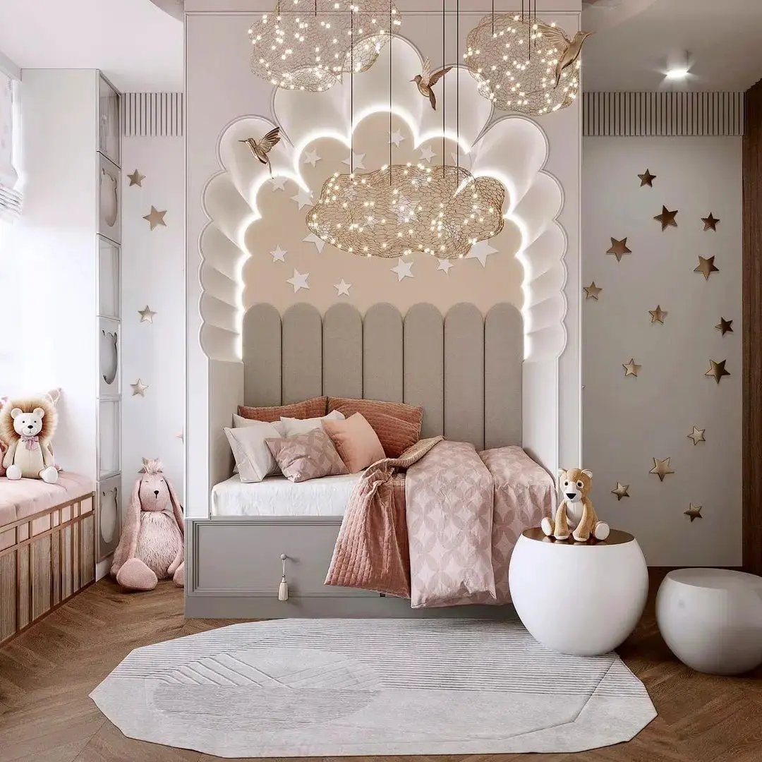 A children's bedroom with a cozy bed, canopy, star-shaped decorations, plush toys, and whimsical lighting. The room features pink, beige, and white hues—a perfect fit for one of those 17 Pink Bedrooms Fit for a Princess. A circular white rug adorns the wooden floor.