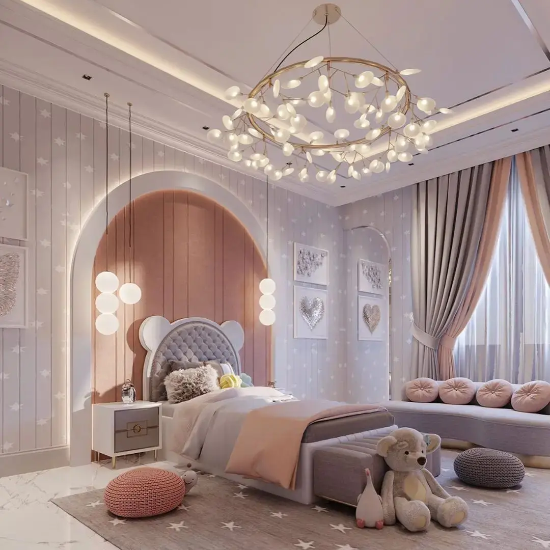 A children's bedroom with a bed, decorative pillows, stuffed toys, and modern lighting fixtures creates an enchanting space. The star-patterned walls and large windows with drapes let light flood in, making it one of the 17 Pink Bedrooms Fit for a Princess.