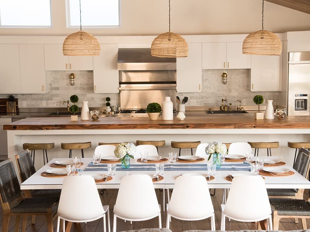 Create a serene oasis in your home with a modern kitchen featuring a large island with a wooden countertop, white cabinets, stainless steel appliances, and a dining table set for eight. Tropical wicker pendant lights hang over the island, adding to the tranquility.