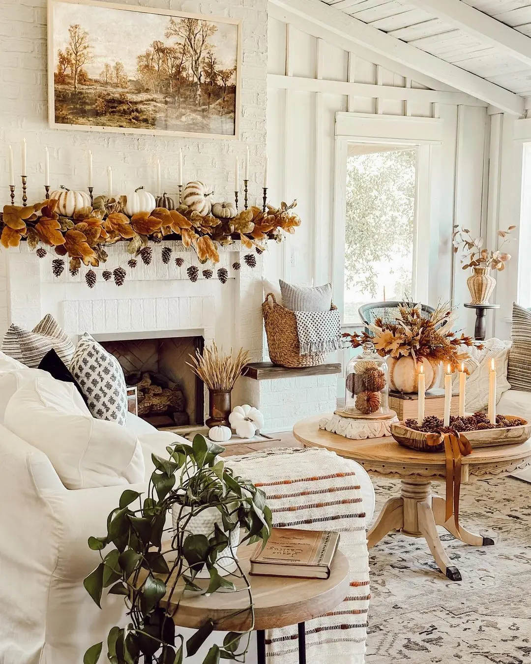 A cozy living room decorated for autumn with white furniture, a white brick fireplace adorned with pumpkins and leaves, and a round coffee table featuring candles and fall-themed decor shows how to avoid common mistakes when decorating for seasonal changes.