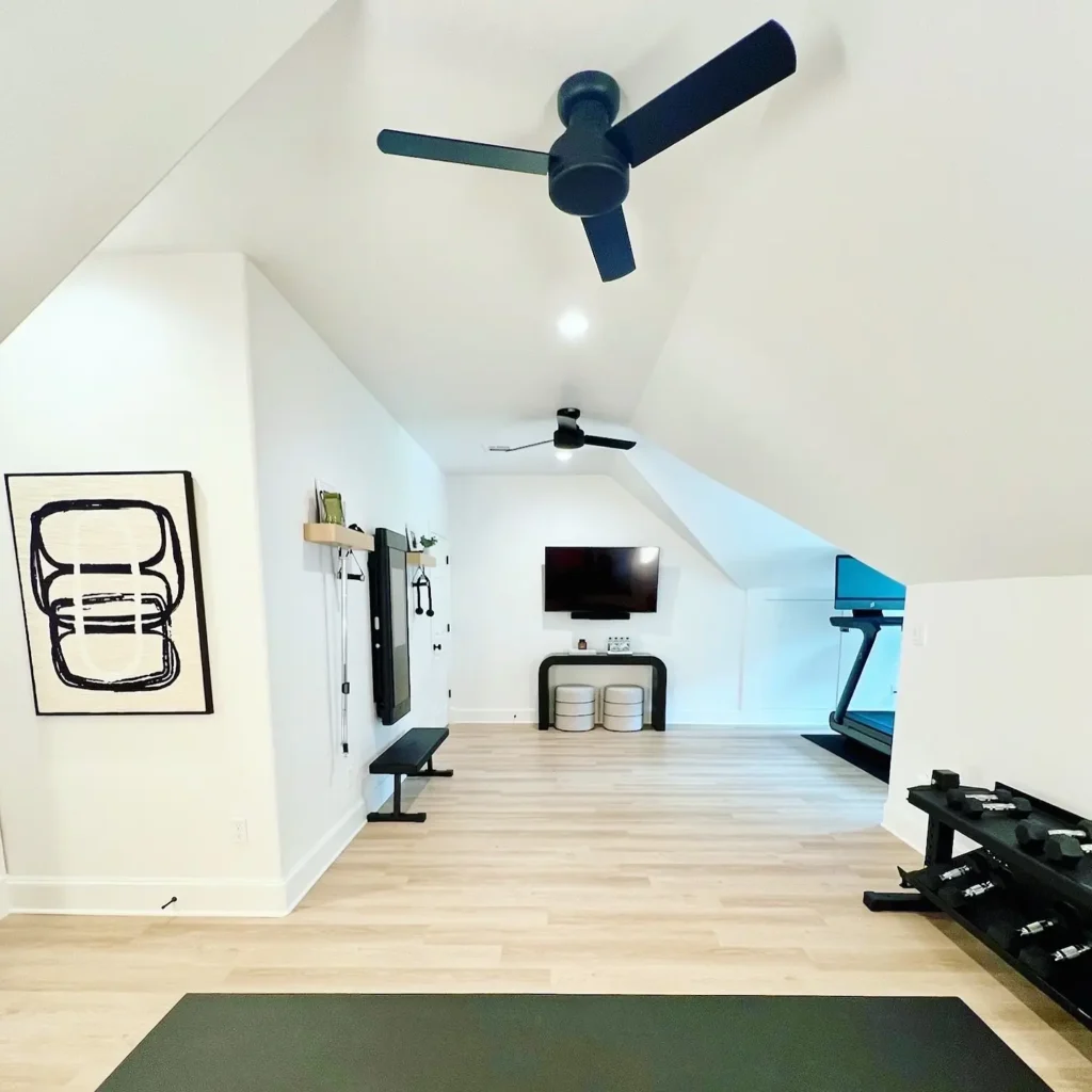 Creating the perfect home gym involves incorporating essentials like a treadmill, dumbbells, and a wall-mounted TV. Here light wooden floors, two ceiling fans, and white walls complete the clean, modern design—ideal tips for every space.